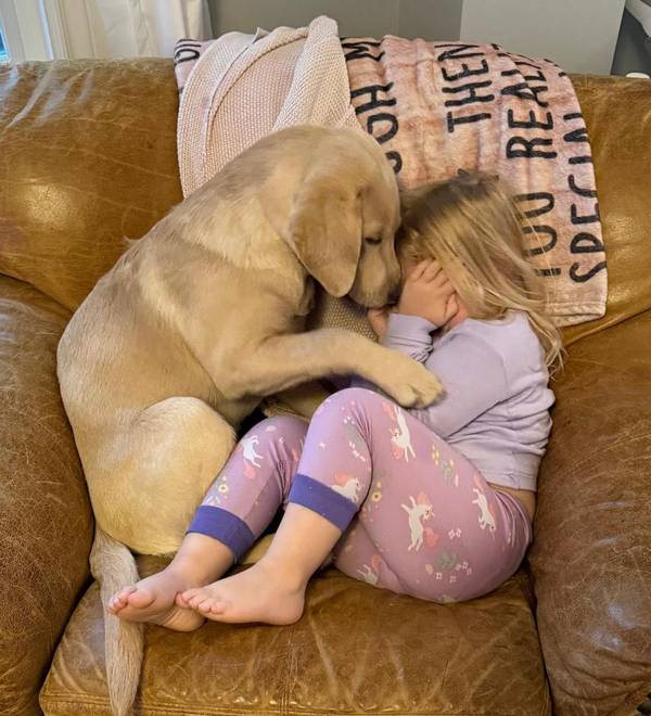 Child cuddling with dog on couch